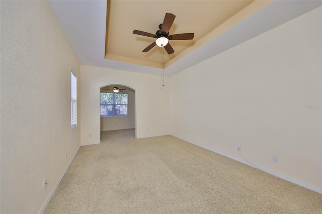 unfurnished room featuring light carpet, ceiling fan, and a tray ceiling