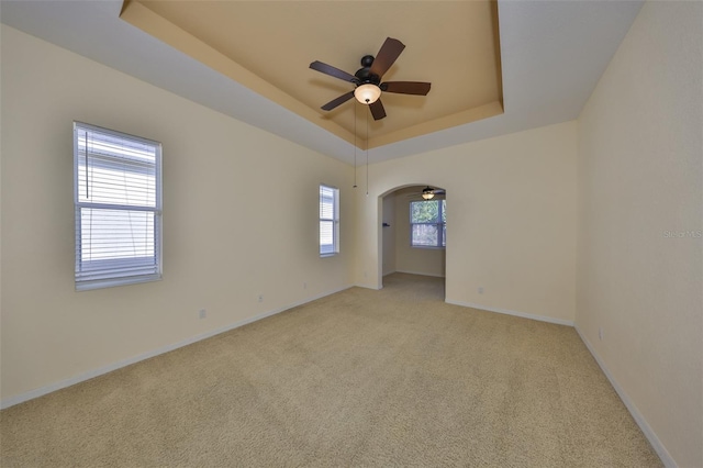 carpeted empty room featuring a raised ceiling and ceiling fan