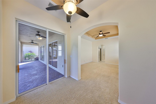 spare room featuring light carpet, ceiling fan, and a tray ceiling