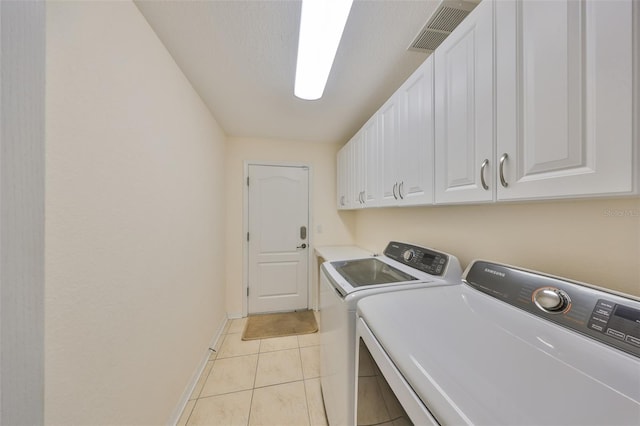 laundry area featuring light tile patterned floors, washing machine and dryer, and cabinets