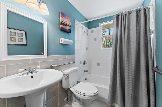 full bathroom featuring shower / bathtub combination with curtain, toilet, sink, and tile walls