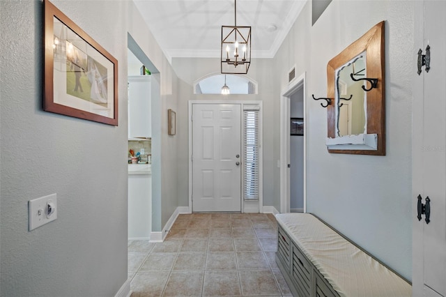 tiled entrance foyer featuring crown molding and a chandelier