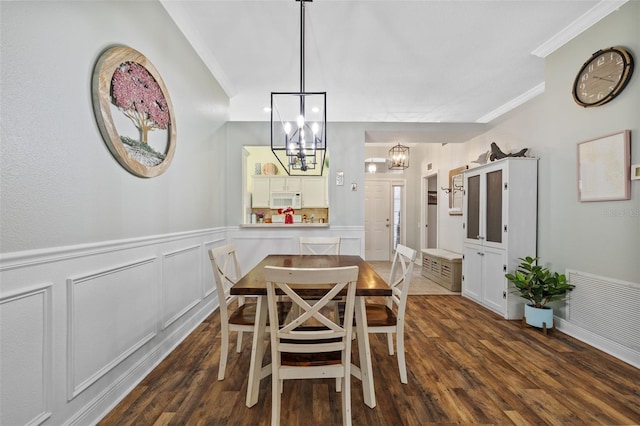 dining area featuring an inviting chandelier, crown molding, and dark hardwood / wood-style flooring