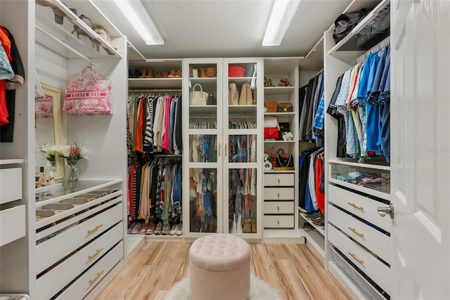 walk in closet with light hardwood / wood-style flooring