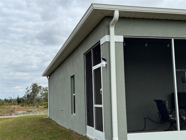 view of home's exterior featuring a sunroom and a lawn