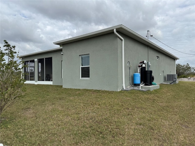 rear view of house featuring a yard, central AC, and a sunroom