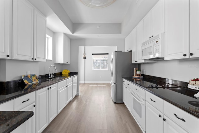 kitchen featuring a tray ceiling, sink, white appliances, and white cabinets