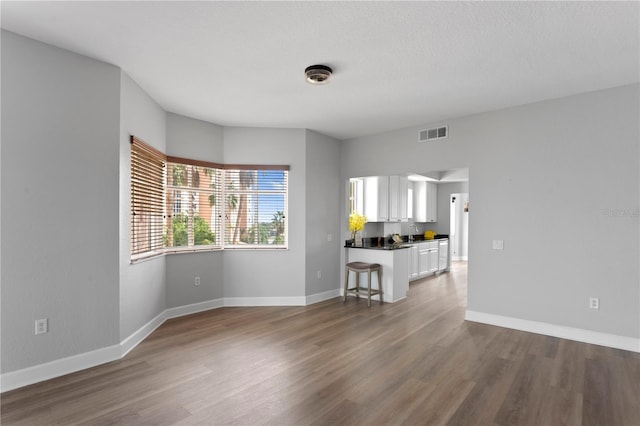 unfurnished living room featuring hardwood / wood-style flooring, sink, and a textured ceiling