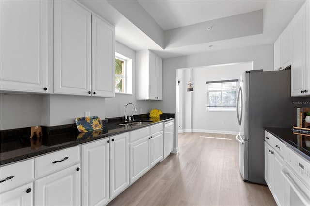 kitchen featuring a tray ceiling, sink, and white cabinets