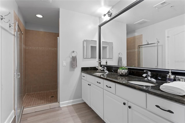 bathroom featuring a tile shower, vanity, and wood-type flooring