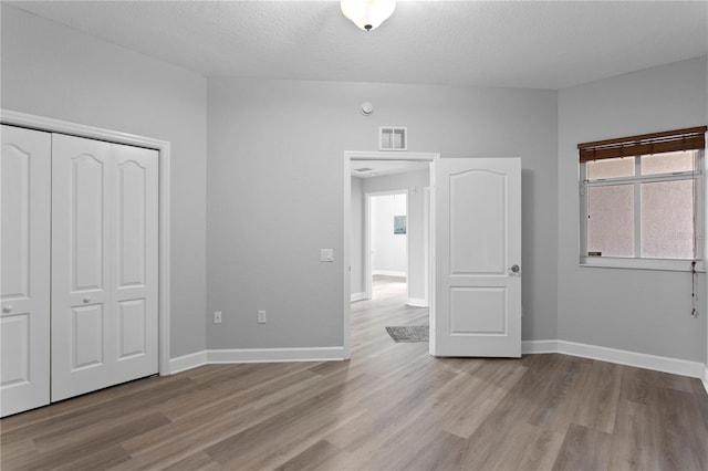 unfurnished bedroom featuring a closet, a textured ceiling, and light wood-type flooring