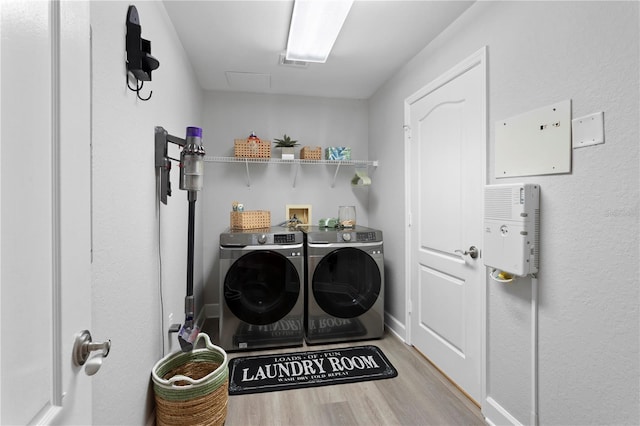 laundry area featuring washing machine and clothes dryer and light wood-type flooring