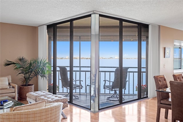 living room with light hardwood / wood-style flooring, floor to ceiling windows, a healthy amount of sunlight, and a water view