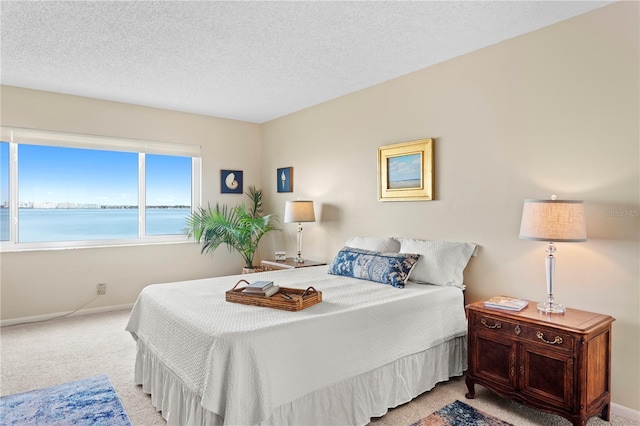 carpeted bedroom with a water view and a textured ceiling