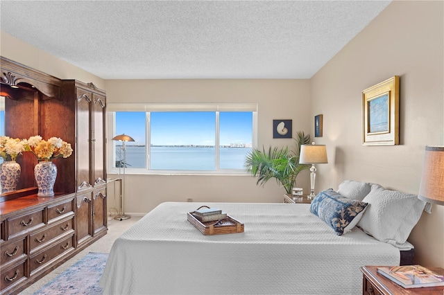 carpeted bedroom featuring a textured ceiling and a water view