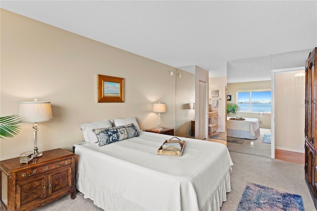 bedroom with a water view, light carpet, and a textured ceiling