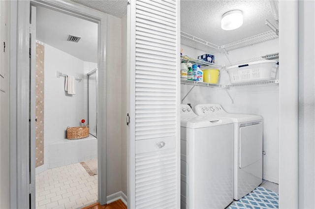 washroom with a textured ceiling and washing machine and clothes dryer