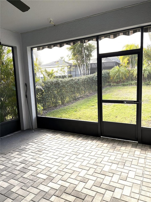 unfurnished sunroom featuring ceiling fan