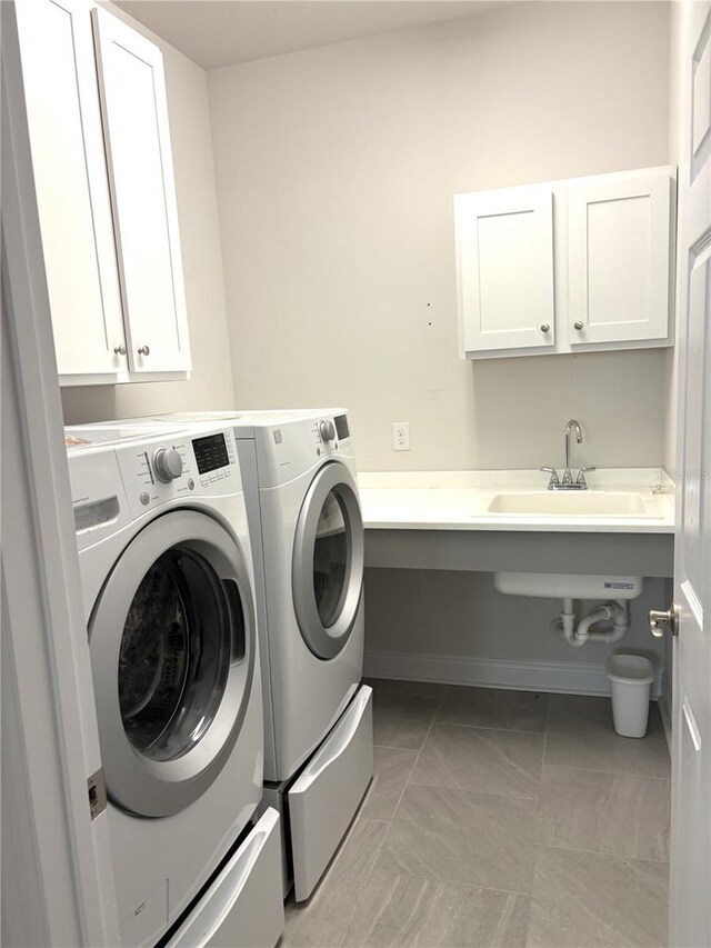 laundry area with cabinets, washer and clothes dryer, and sink