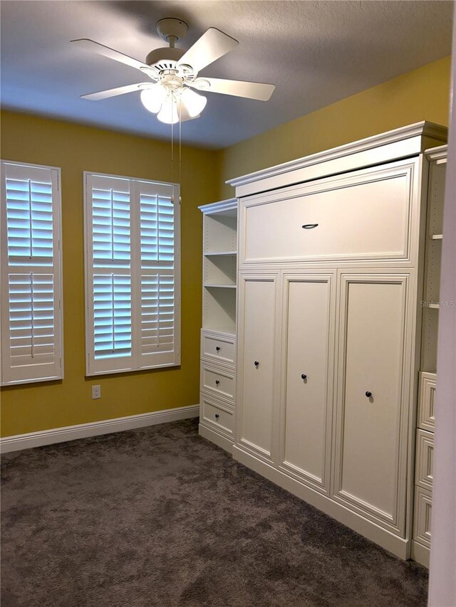 unfurnished bedroom with dark carpet and ceiling fan