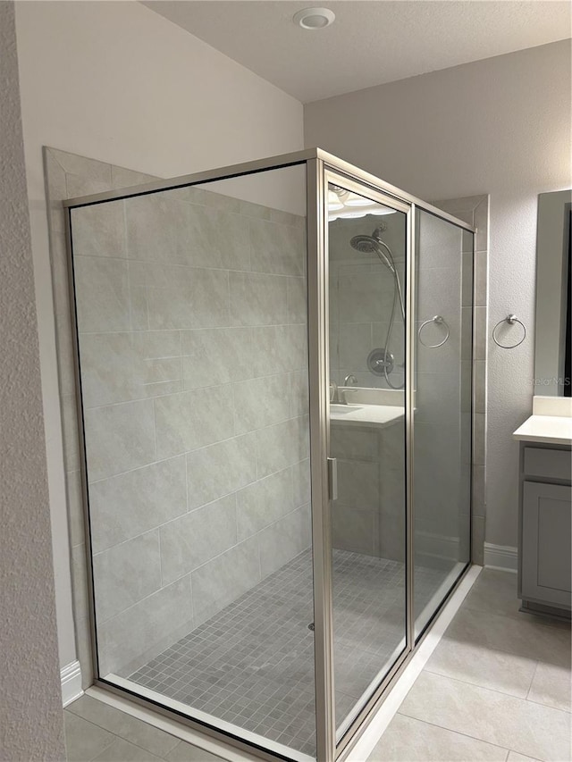 bathroom with walk in shower, vanity, and tile patterned flooring