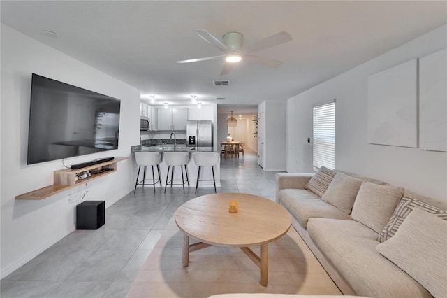 living room featuring light tile patterned flooring, ceiling fan, and sink