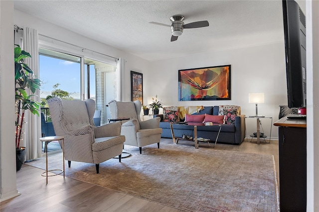 living room featuring ceiling fan, a textured ceiling, and light wood-type flooring