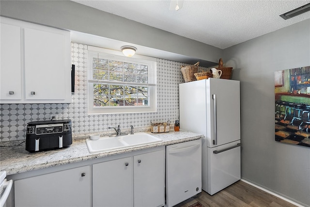 kitchen with dark hardwood / wood-style flooring, sink, white appliances, and white cabinets