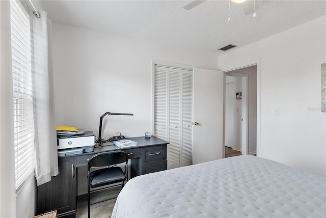 bedroom featuring ceiling fan, hardwood / wood-style floors, a textured ceiling, and a closet