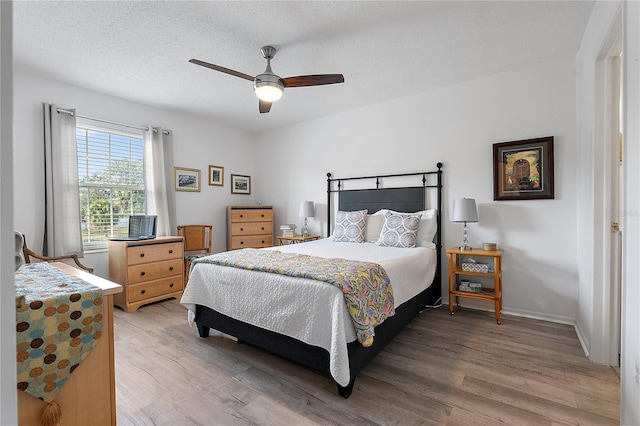 bedroom with hardwood / wood-style flooring, ceiling fan, and a textured ceiling