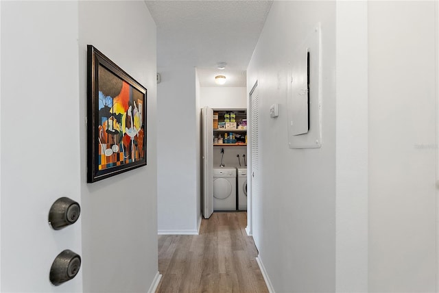 corridor featuring washer and clothes dryer, light hardwood / wood-style floors, and a textured ceiling