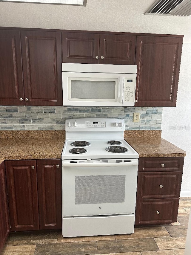 kitchen with dark hardwood / wood-style flooring, backsplash, and white appliances