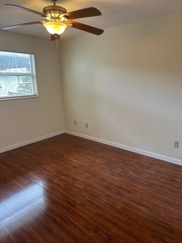 spare room featuring dark wood-type flooring, ceiling fan, and a textured ceiling