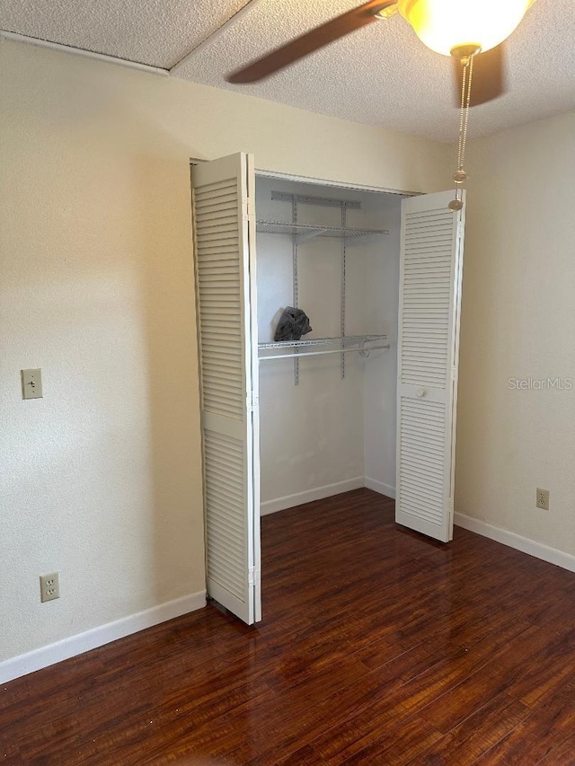 unfurnished bedroom with dark hardwood / wood-style flooring, ceiling fan, a closet, and a textured ceiling