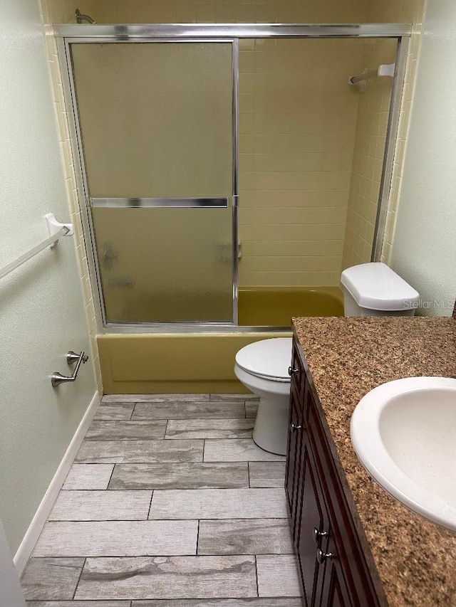 full bathroom featuring enclosed tub / shower combo, vanity, and toilet