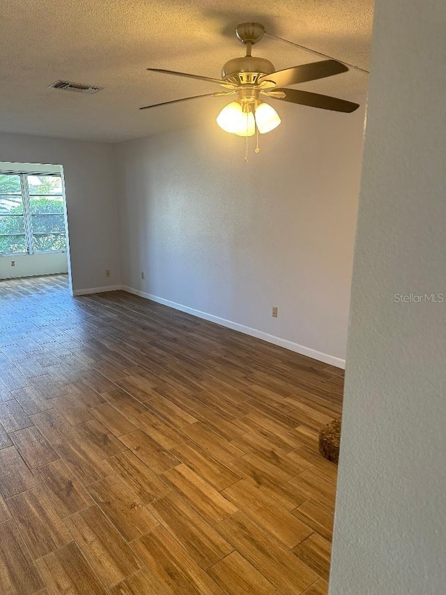 unfurnished room with ceiling fan, hardwood / wood-style flooring, and a textured ceiling