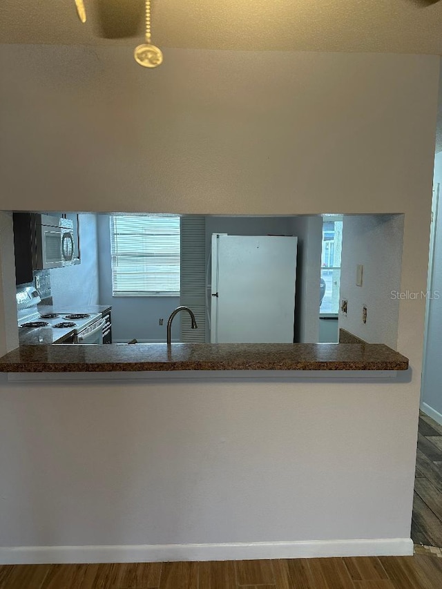 kitchen with sink, white appliances, kitchen peninsula, and hardwood / wood-style flooring