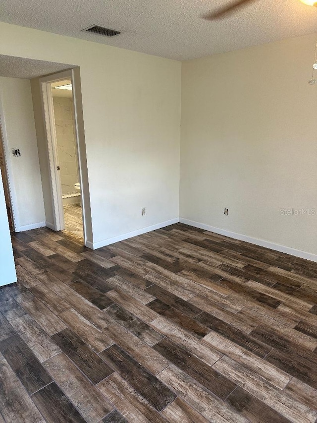 spare room featuring a textured ceiling and dark hardwood / wood-style flooring