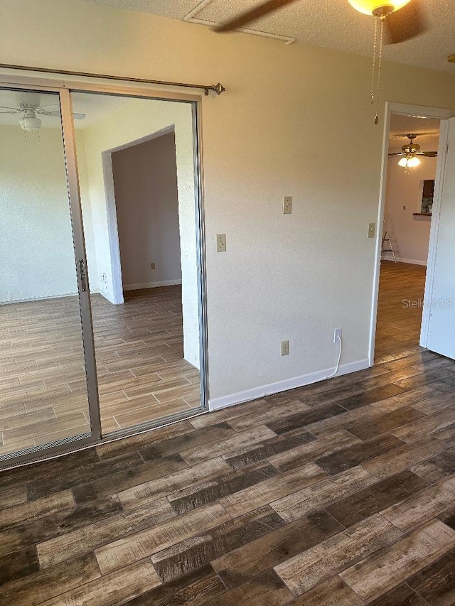 unfurnished room with ceiling fan, dark wood-type flooring, and a textured ceiling