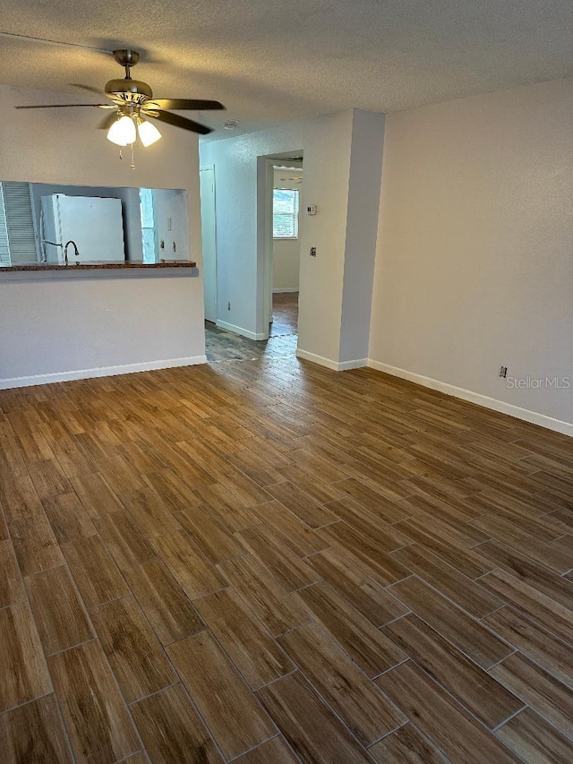 unfurnished living room with ceiling fan, dark hardwood / wood-style flooring, and a textured ceiling