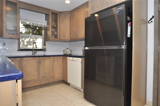 kitchen with sink, light tile patterned floors, stainless steel refrigerator, white dishwasher, and decorative backsplash