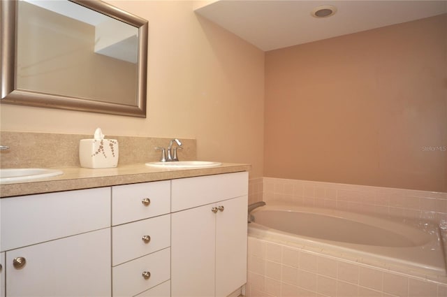 bathroom with tiled tub and vanity