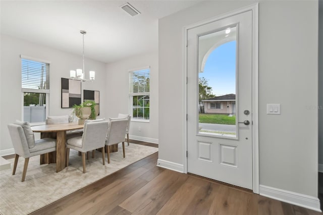 dining room with dark hardwood / wood-style flooring and an inviting chandelier