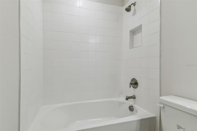 bathroom featuring toilet and tiled shower / bath