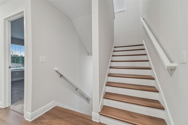 stairs featuring vaulted ceiling and hardwood / wood-style floors