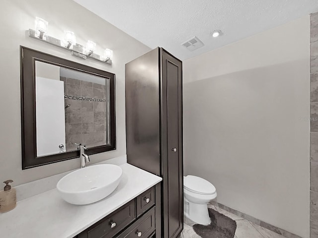 bathroom with vanity, toilet, and a textured ceiling