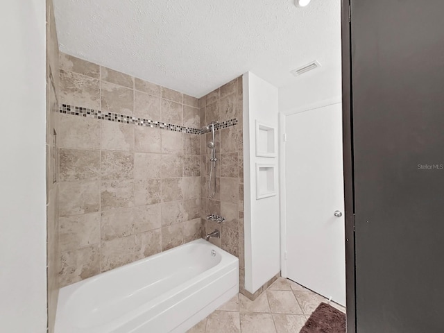 bathroom with tiled shower / bath combo, tile patterned flooring, and a textured ceiling