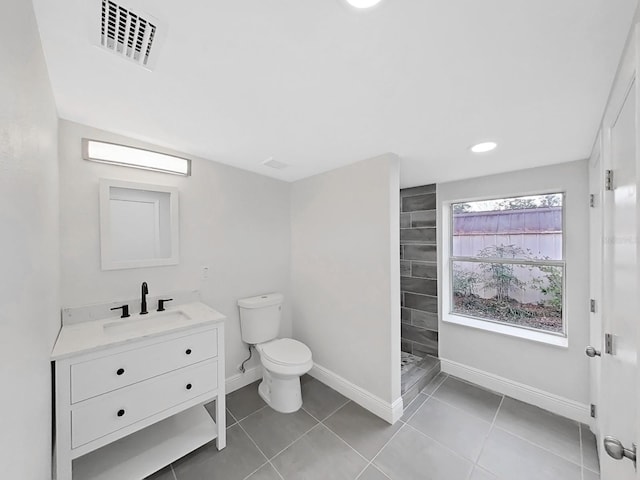 bathroom with vanity, toilet, tile patterned flooring, and a tile shower