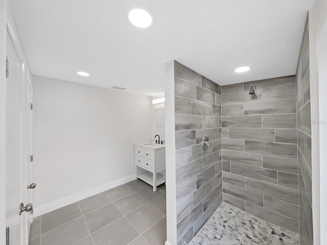 bathroom featuring tile patterned flooring, vanity, and a tile shower