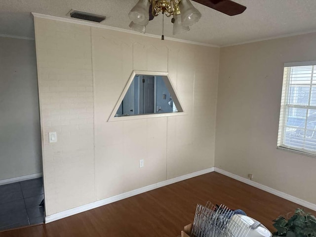 spare room with crown molding, ceiling fan, dark wood-type flooring, and a textured ceiling